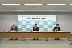 町長を含めた代表者3名が締結式を行っている様子