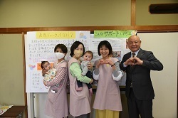 産後ドゥーラの方が赤ちゃんも抱っこして、町長との写真を撮る様子